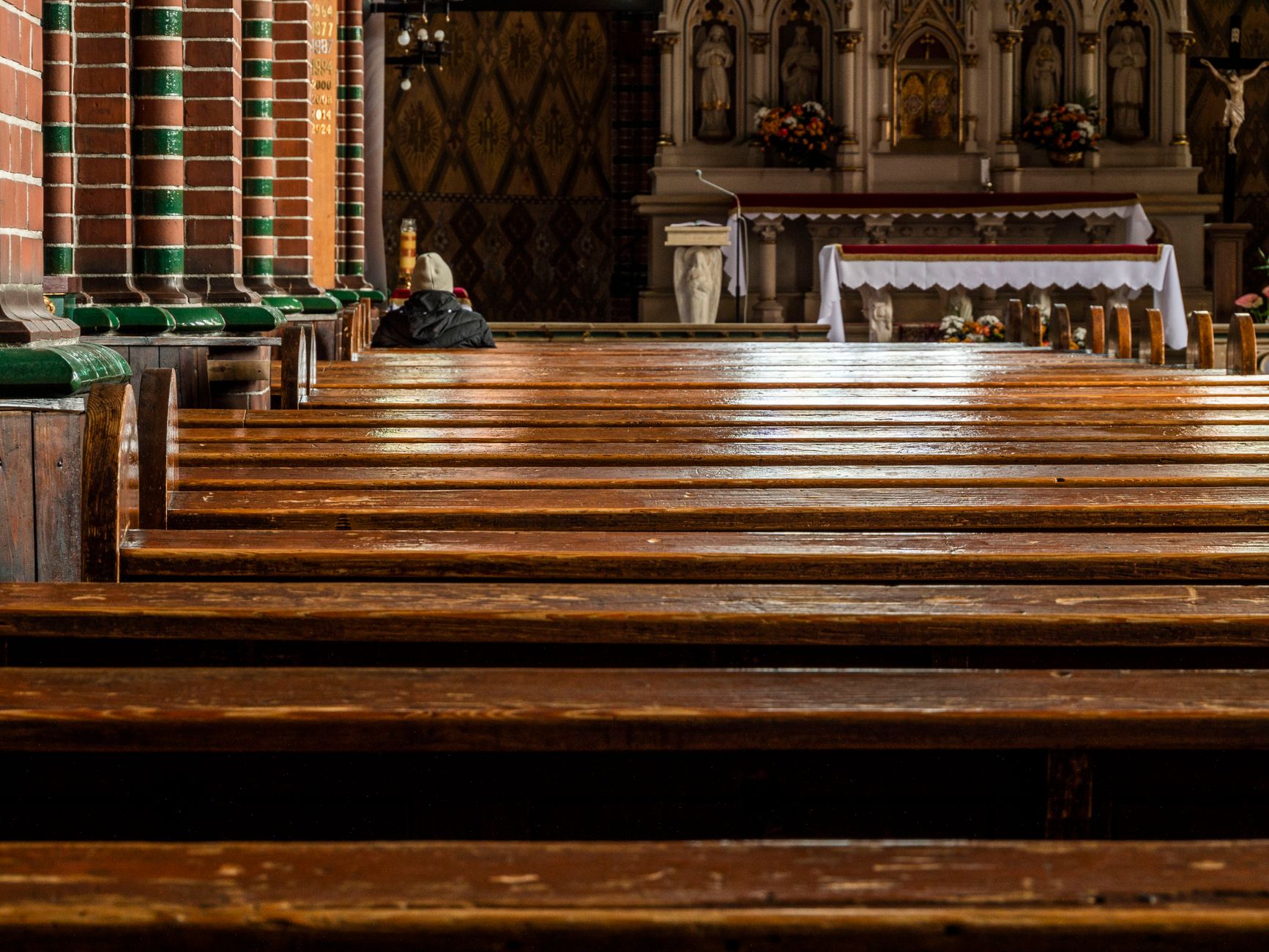 Empty church interior with wooden pews leading to a richly decorated altar