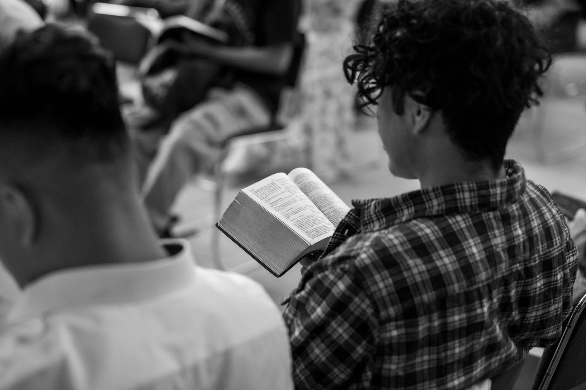 A courthouse, statue of justice, and capitol building overlooking a diverse group of people — lawyer, nurse, police officer, families and volunteers — gathered around a glowing open Bible, symbolizing the Bible's influence on society and public life